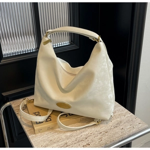 Détail du sac cabas blanc cassé avec logo et finitions dorées sur fond de marbre