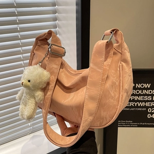 Bolso hobo plisado rosa con colgante de oso mostrado en un entorno de estudio suave