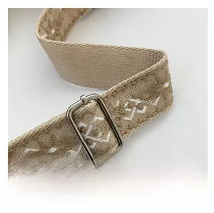 Detail of adjustable woven shoulder strap with geometric patterns and silver metal buckle
