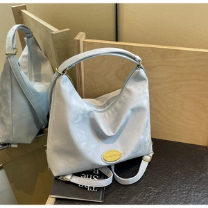 Détail du sac cabas bleu clair avec étiquette jaune et finitions métalliques dorées