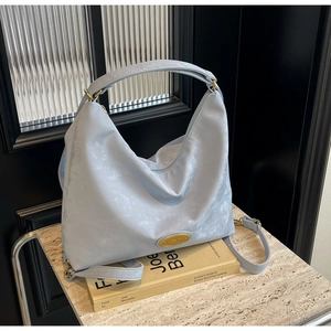 Détail du sac cabas bleu clair montrant la texture nylon et la plaque logo dorée