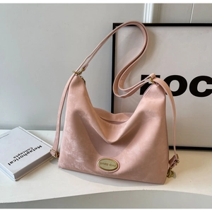 Détail d'un sac cabas en daim rose mat avec logo doré et large bandoulière réglable