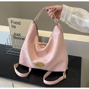 Gros plan détaillé du sac cabas en cuir rose givré avec plaque de logo dorée élégante