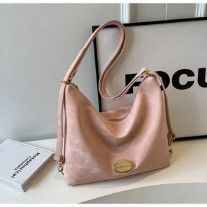 Détail d'un sac cabas en daim rose avec logo métallique doré et texture souple et douce