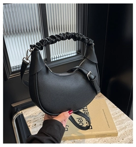 Detail of black lychee grain crescent bag featuring a scrunchie handle and leather strap