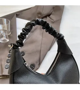Detail of black lychee grain leather dumpling bag with pleated handle and silver zipper