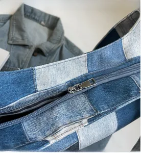 Close-up of smooth silver metal zipper on a blue denim patchwork tote bag with striped lining