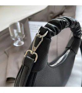 Detail of black litchi grain leather texture and silver metal hardware of the handbag