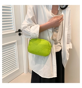 Detail of neon green crossbody bag with embossed floral pattern and jacquard strap