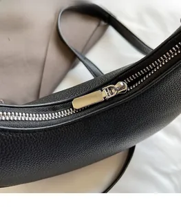 Detail of silver metal zipper and black lychee grain leather texture on crossbody bag