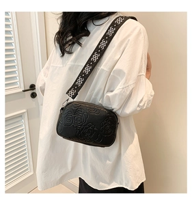 Close-up of black PU leather crossbody bag with 3D rose relief and jacquard strap