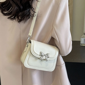 Chique crème crossbodytas met zilveren strik gedragen door model in pak