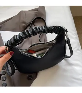 Black lychee leather crescent bag with pleated handle showing inner storage capacity
