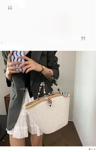 Detail of straw woven tote bag with colorful silk scarf handle and wooden bead accents