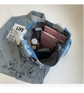 Spacious interior of blue denim tote bag with striped lining and daily essentials