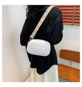 Detail of white embossed rose crossbody bag featuring a stylish embroidered wide strap
