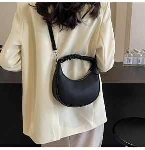 Detail of black dumpling bag featuring ruched handle and pebbled faux leather texture