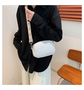 Detail of white PU crossbody bag with 3D floral texture and woven geometric strap