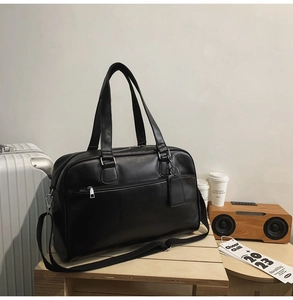 Detail of black matte leather tote bag with metal zipper and adjustable strap