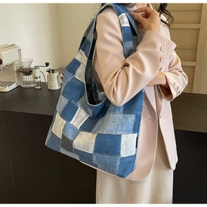 Detailed patchwork denim tote bag shown worn by a model in a cozy interior setting