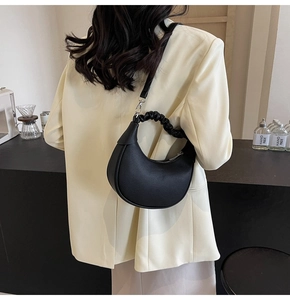 Detailed view of black ruched handle hobo bag worn over the shoulder in a lifestyle setting