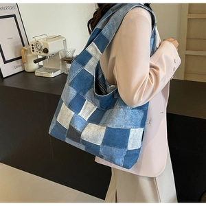 Detail of blue denim patchwork tote bag with stitching on a shoulder hobo bag