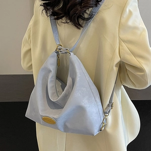 Sac hobo bleu clair minimaliste en cuir souple avec détails dorés porté par un mannequin