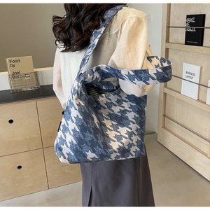Close-up of blue houndstooth tote bag featuring wide straps and striped fabric lining