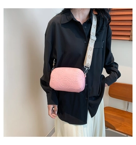 Detail of pink small square bag with embossed rose pattern and wide jacquard strap