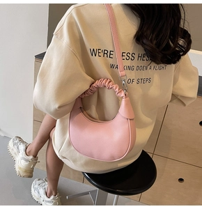 Pink crescent bag with cloud-like pleats and lychee texture shown in a casual side view
