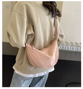 Detail view of pink crescent canvas bag with adjustable strap on a model back