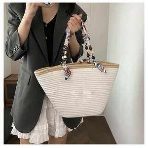 Detail of straw tote bag featuring silk scarf handle and decorative wooden beads
