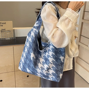Detailed view of blue and white houndstooth canvas tote bag worn on shoulder by a model