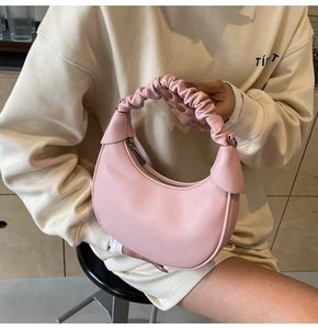 Detail of pink hobo bag featuring pebbled leather and pleated cloud-style handle