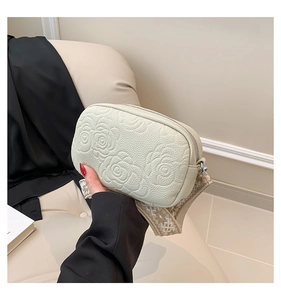 Detail of floral embossed cream crossbody bag with patterned jacquard wide strap