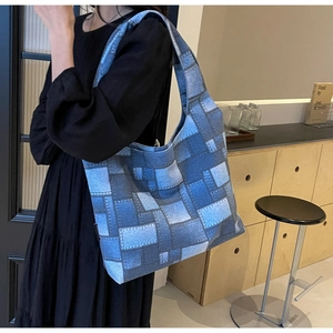 Close-up of blue denim patchwork tote bag showing fabric texture and side brand tag