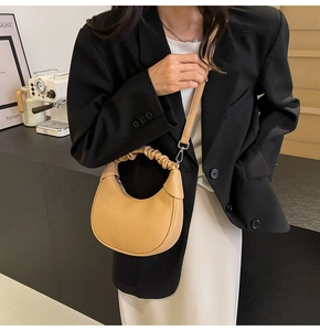 Detail of light tan croissant bag with ruched handle and detachable crossbody strap
