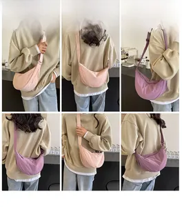 Detail view of pink and purple canvas dumpling bags worn cross-body in a cozy cafe