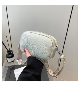 Detail of cream white leather bag with rose embossing and geometric wide strap