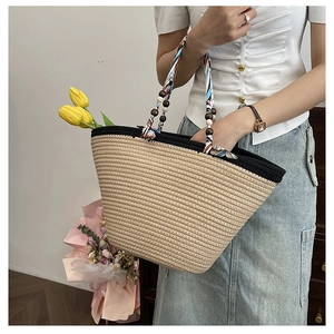 Detail of straw tote bag featuring decorative silk scarf handle and wooden beads