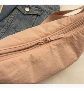 Detail shot of smooth zipper closure on the pink nylon crossbody dumpling bag