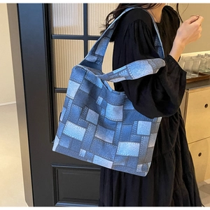 Blue denim patchwork tote bag with wide shoulder strap shown on a model