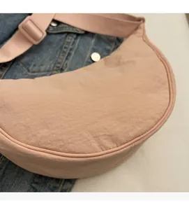 Detail of pink crescent bag showing crinkled nylon fabric and adjustable strap