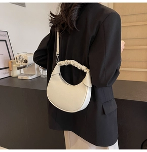 Detail of white lychee leather dumpling bag featuring a unique ruched top handle design