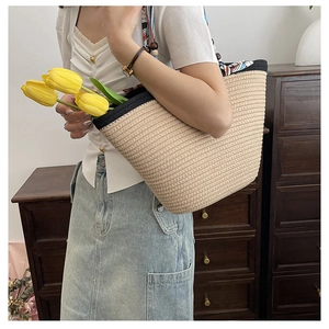 Close-up of straw woven tote bag featuring silk scarf handle and wooden bead accents