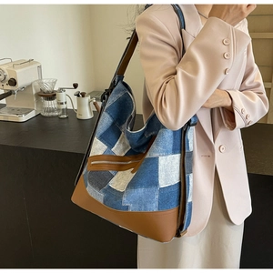 Detail of blue denim patchwork tote bag with brown leather straps and vintage zipper