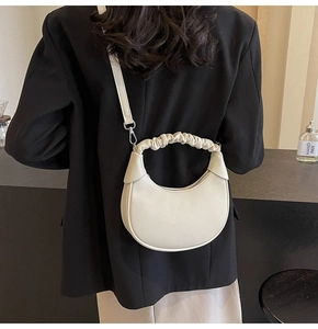 Detail of off-white crescent dumpling bag with pleated cloud handle on female model