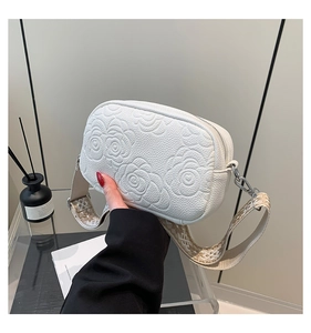 Detail of white square crossbody bag with embossed rose pattern and jacquard strap