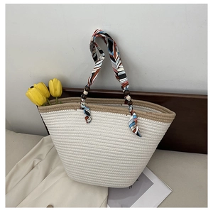 Close-up of woven straw tote bag featuring silk scarf handle and decorative wood beads