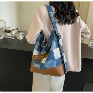 Detail of blue and white checkered denim tote bag with brown leather base on model